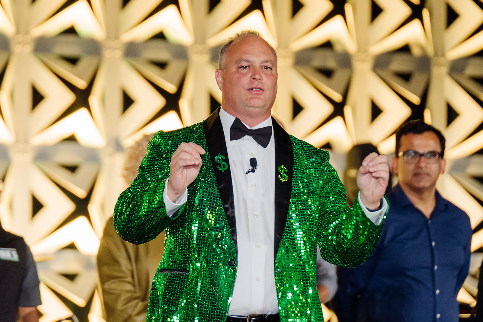 A formally dressed event host welcomes guests during a corporate celebration